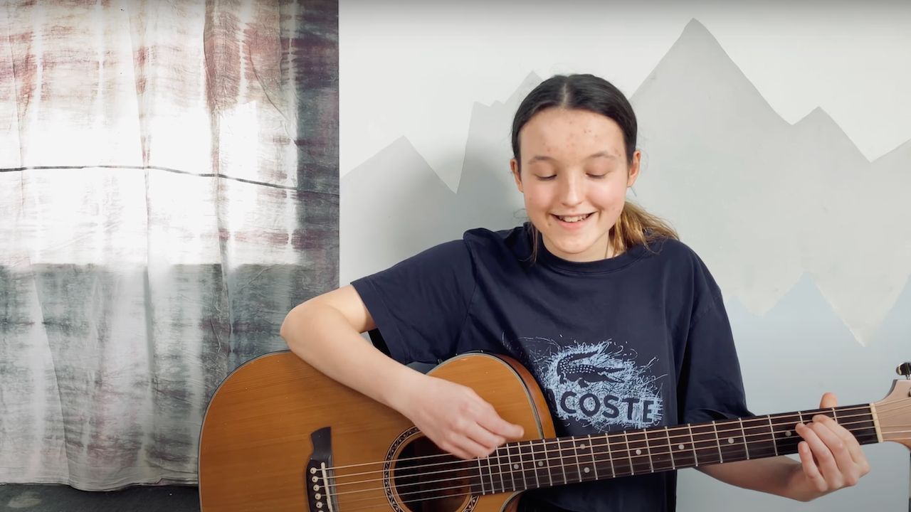 Bella Ramsey tocando la guitarra.